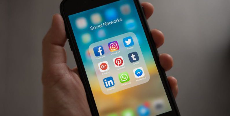 Social Media - Person Holding Iphone Showing Social Networks Folder