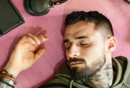 Solar-Powered Gadgets - A Man with Hoodie Jacket Lying Beside the Gadgets