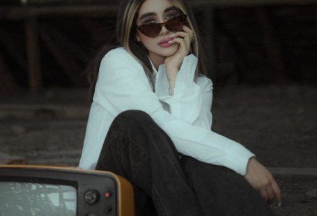 4K TV - A Woman Sitting beside a Vintage Television