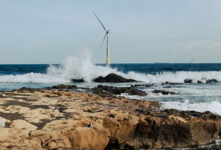 Energy-Efficient - A wind turbine on the beach with waves crashing in the background