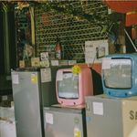 A storefront display featuring vintage televisions and home appliances on a sunny day in Bangkok.
