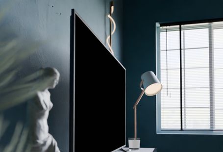 A stylish modern room featuring a statue, flat screen TV, and window light.