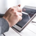 Close-up of a hand using a stylus on a tablet, showcasing digital technology interaction.