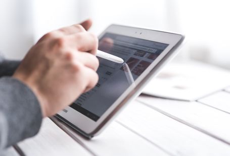Close-up of a hand using a stylus on a tablet, showcasing digital technology interaction.