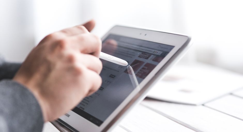 Close-up of a hand using a stylus on a tablet, showcasing digital technology interaction.
