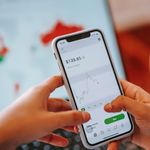Mobile Apps Manage Finances — Crop anonymous trader using app on cellphone with graph and dollar price on screen in house