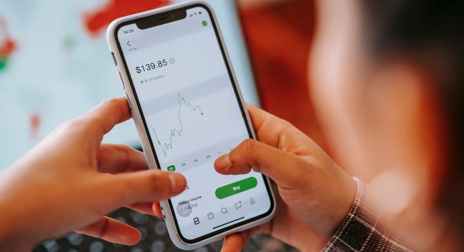Mobile Apps Manage Finances — Crop anonymous trader using app on cellphone with graph and dollar price on screen in house
