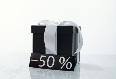 Elegant black gift box tied with a white ribbon, featuring a 50% discount tag.