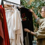 Fashion enthusiast browsing clothing rack in boutique store, selecting attire.