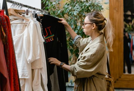 Fashion enthusiast browsing clothing rack in boutique store, selecting attire.