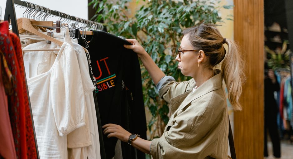 Fashion enthusiast browsing clothing rack in boutique store, selecting attire.