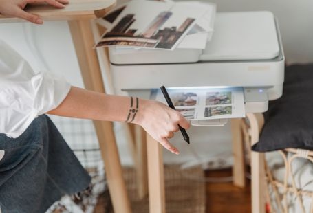 High angle of crop anonymous female photographer using printer for making images while working in flat