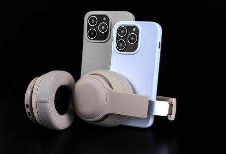 Pair of smartphones with beige headphones on black background, showcasing modern technology.