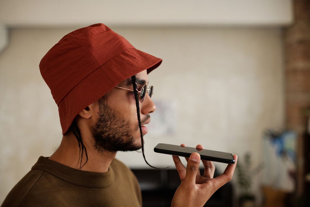 Profile view of a man in a red bucket hat talking on a smartphone indoors.