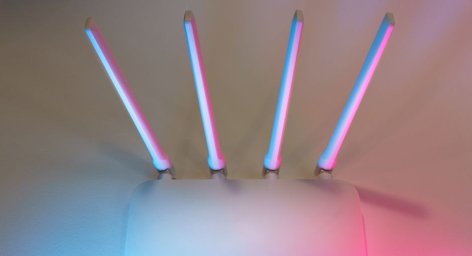Sleek white wireless router with four antennas emitting soft blue and pink light.