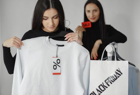 Two women enjoying Black Friday shopping with discounts and deals on clothes.