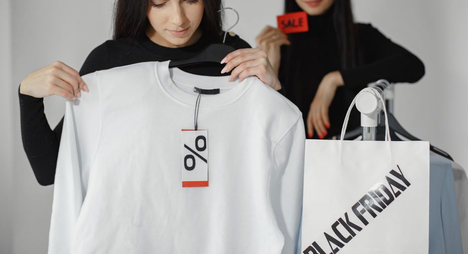 Two women enjoying Black Friday shopping with discounts and deals on clothes.