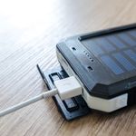 A close-up of a solar charger with a USB connection on a wooden surface, showcasing modern technology.