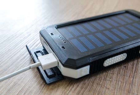 A close-up of a solar charger with a USB connection on a wooden surface, showcasing modern technology.