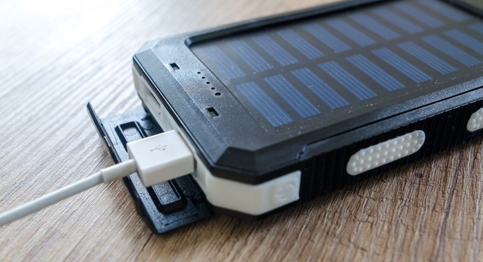 A close-up of a solar charger with a USB connection on a wooden surface, showcasing modern technology.